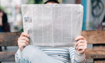 man sitting on bench reading newspaper