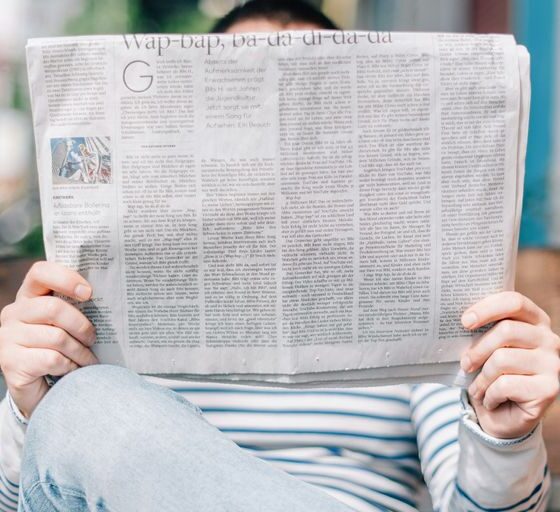 man sitting on bench reading newspaper