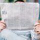 man sitting on bench reading newspaper