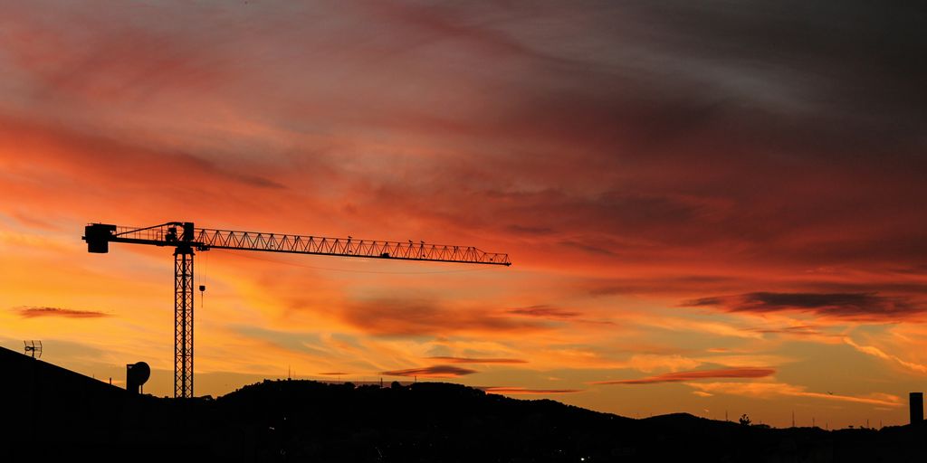 silhouette of crane and hill under cloudy sky photo taken during sunset