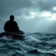 A figure in a boat on rough waters.