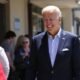 Biden in line at polling station, smiling while voting.