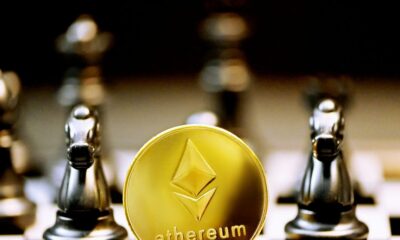 a gold ethereum coin sitting on top of a chess board