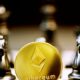 a gold ethereum coin sitting on top of a chess board