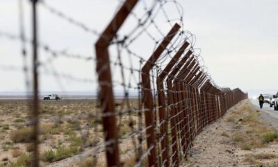 Empty US-Mexico border with barbed wire and vehicles.