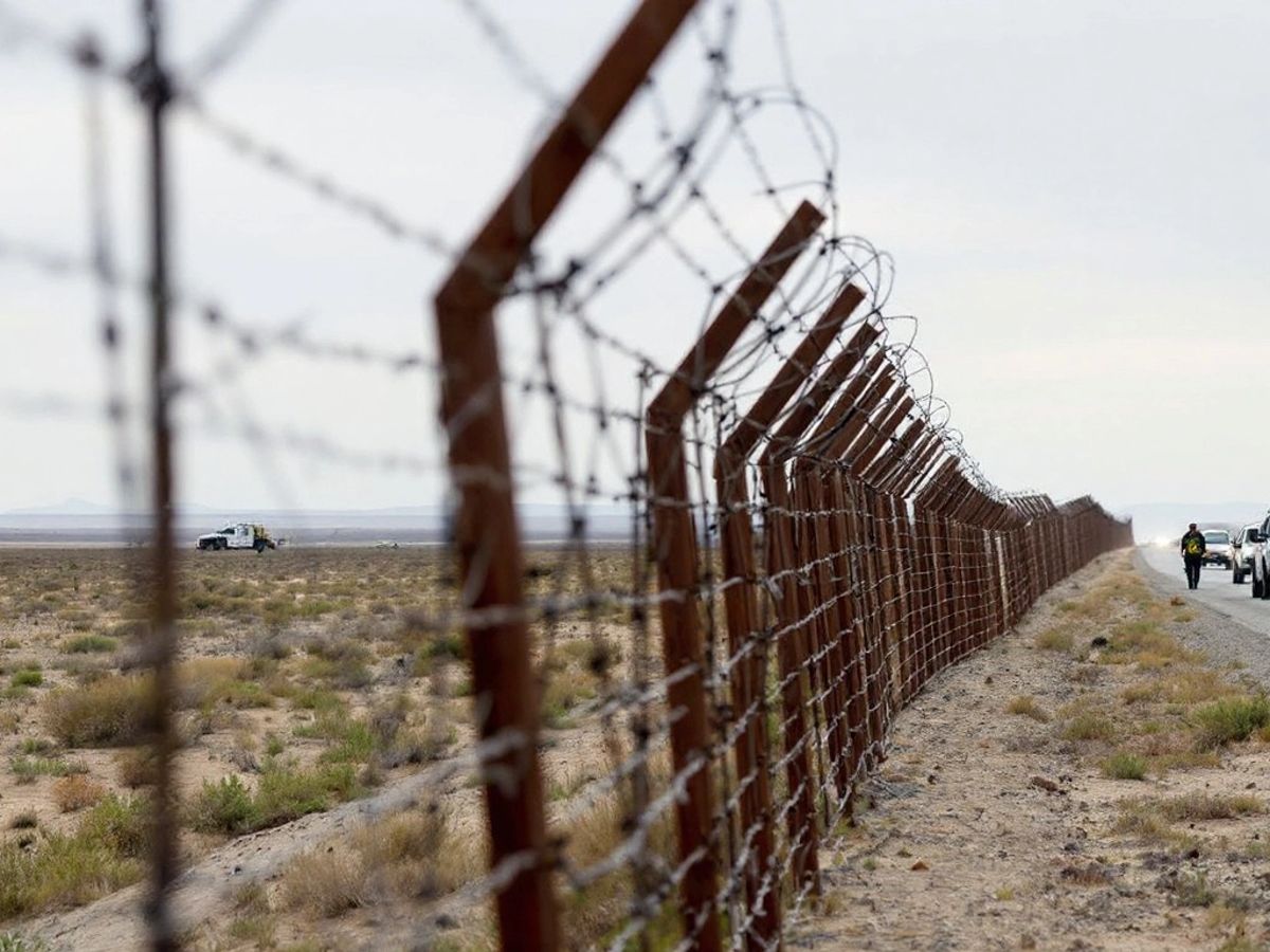 Empty US-Mexico border with barbed wire and vehicles.