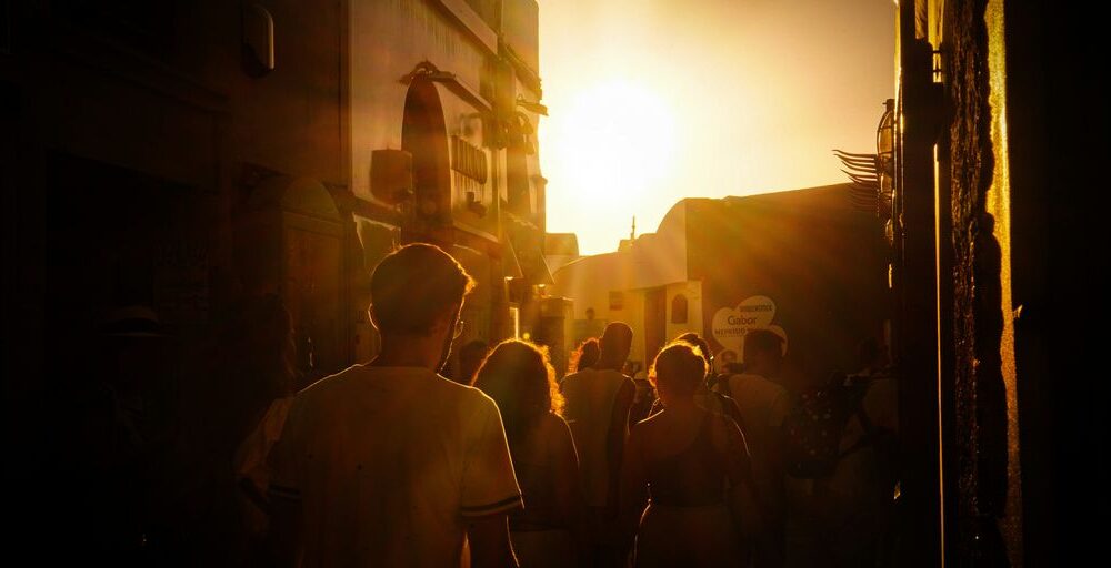 a group of people walking down a street at sunset