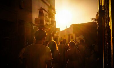 a group of people walking down a street at sunset