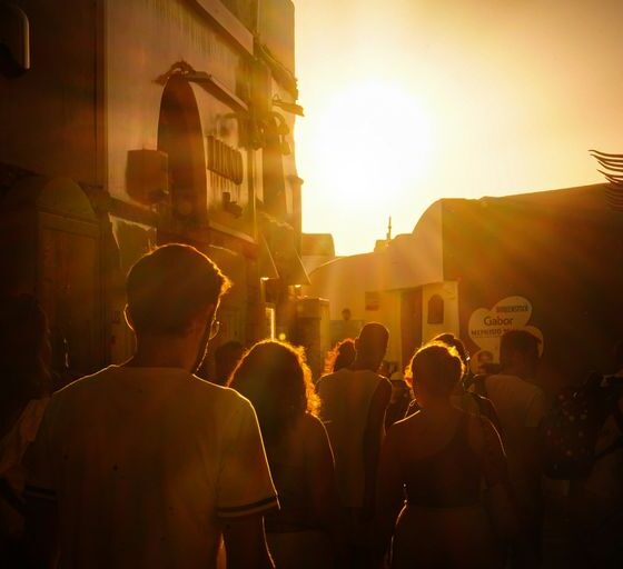 a group of people walking down a street at sunset