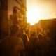 a group of people walking down a street at sunset