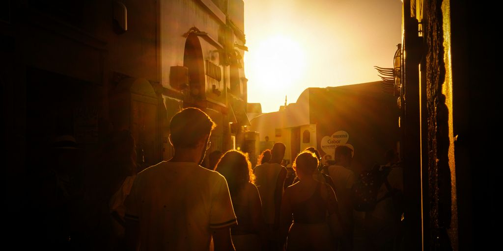 a group of people walking down a street at sunset