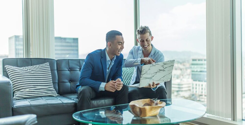 two men in suit sitting on sofa