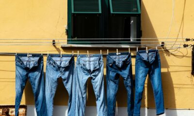 five blue denim jeans hanged on grey cable near window