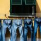 five blue denim jeans hanged on grey cable near window