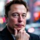 Elon Musk deep in thought, urban backdrop blurred.