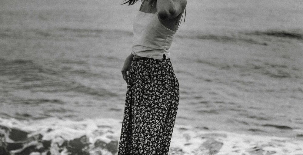 grayscale photography of woman standing on shore