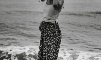 grayscale photography of woman standing on shore