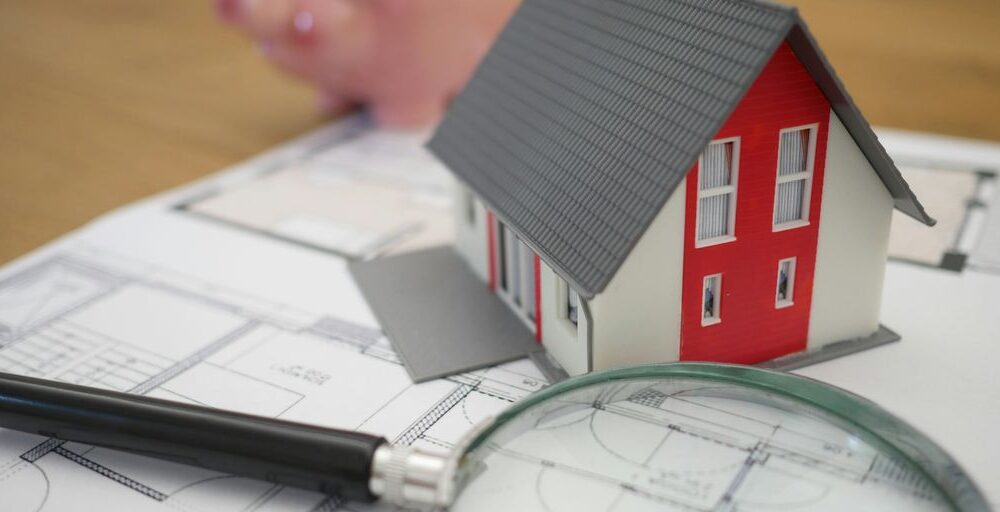 white and red wooden house beside grey framed magnifying glass