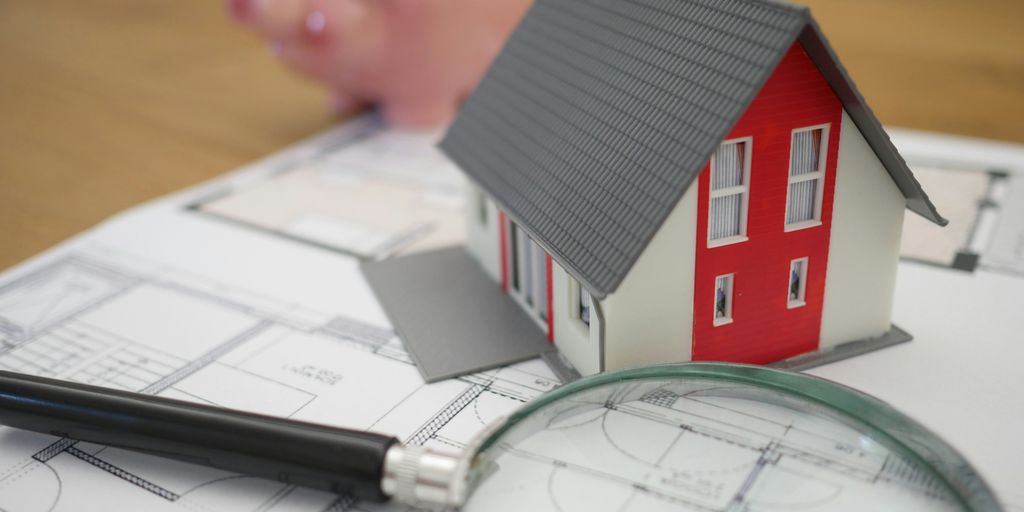 white and red wooden house beside grey framed magnifying glass