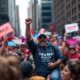 Crowd at NYC rally with flags and merchandise.