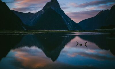 photo of lake with reflection of mountains under cloudy sky