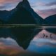 photo of lake with reflection of mountains under cloudy sky