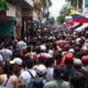 Crowded Miami street with Venezuelan flags and diverse people.