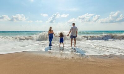 man, woman and child holding hands on seashore