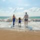 man, woman and child holding hands on seashore