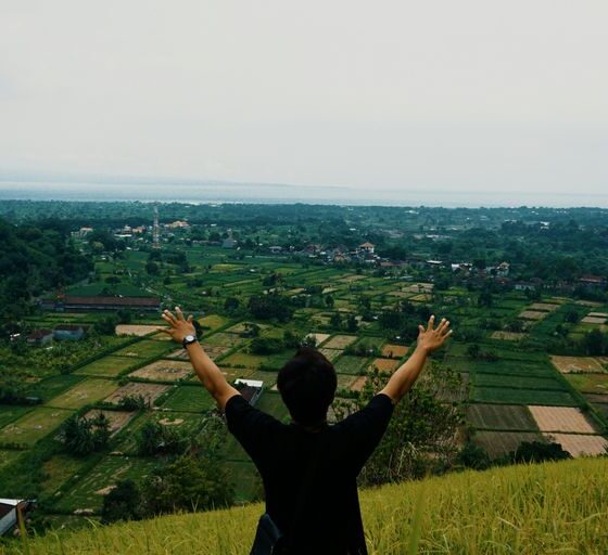 a man standing on top of a lush green hillside