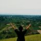 a man standing on top of a lush green hillside