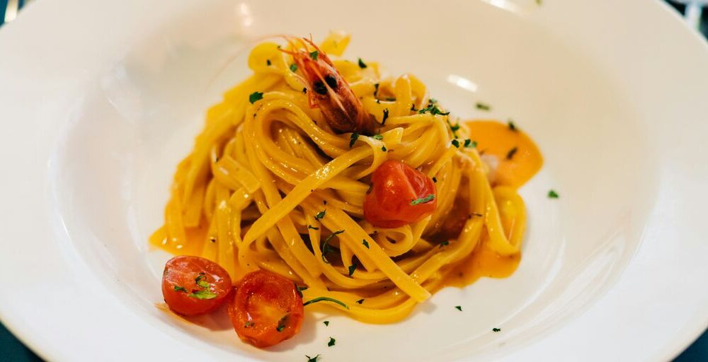 a plate of pasta with shrimp and tomatoes