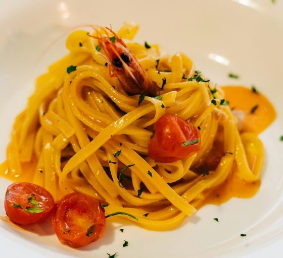 a plate of pasta with shrimp and tomatoes