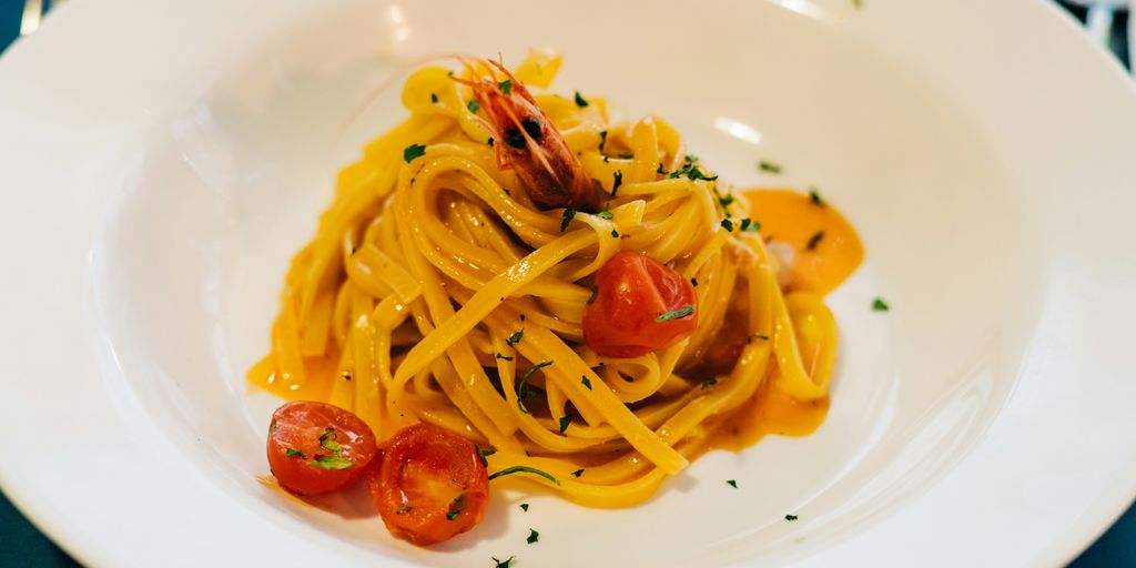 a plate of pasta with shrimp and tomatoes