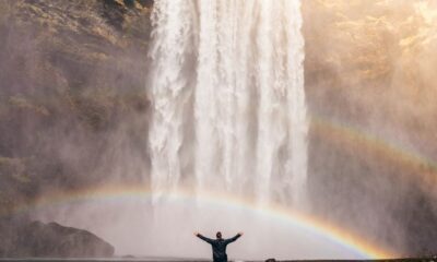 person in front of waterfalls with double rainbow during daytime