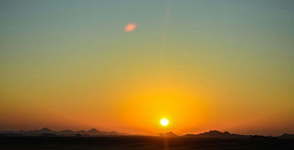 the sun is setting over the mountains in the desert