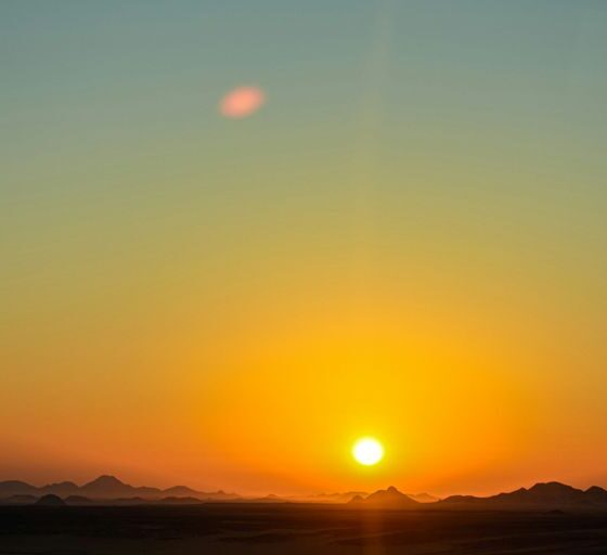 the sun is setting over the mountains in the desert