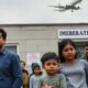 Family outside immigration office during deportation controversy.