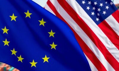 U.S. and EU flags intertwined at a busy trade port.