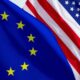 U.S. and EU flags intertwined at a busy trade port.