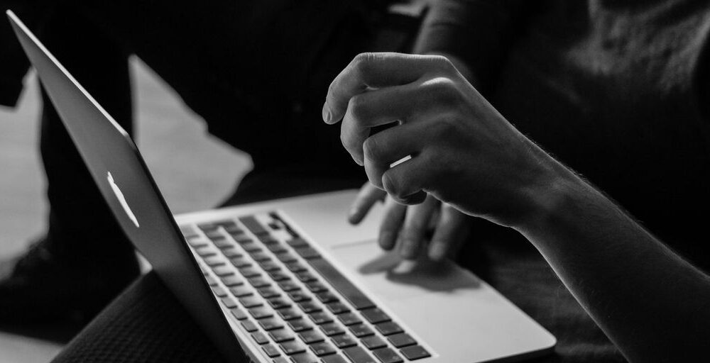 grayscale photo of person using MacBook