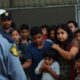 Immigration detention center with distressed families and agents.