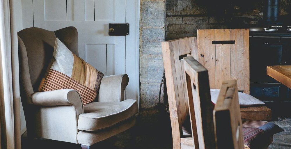 gray wing chair with throw pillows beside white door
