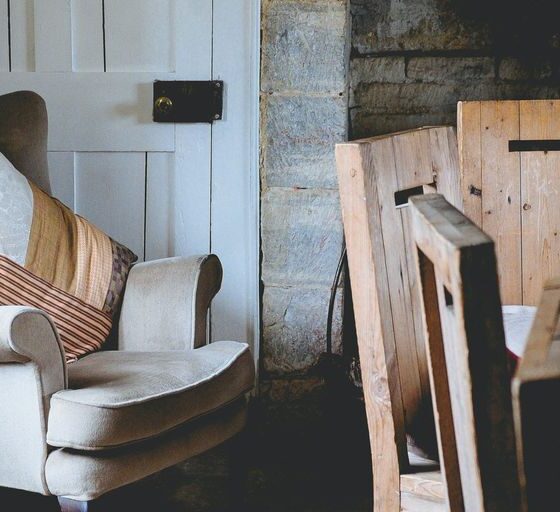 gray wing chair with throw pillows beside white door
