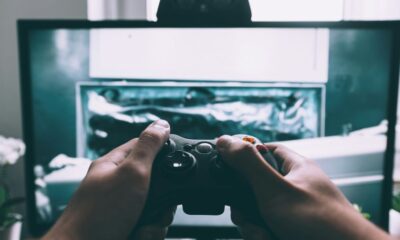 person holding game controller in-front of television