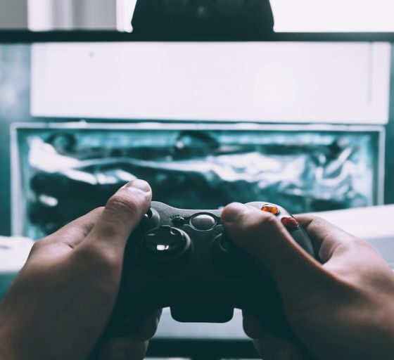 person holding game controller in-front of television