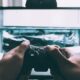 person holding game controller in-front of television