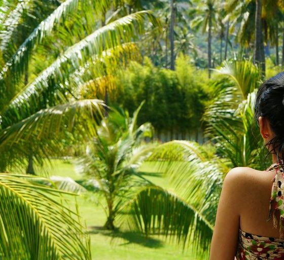 A woman looking out a window at a lush green forest