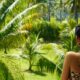 A woman looking out a window at a lush green forest
