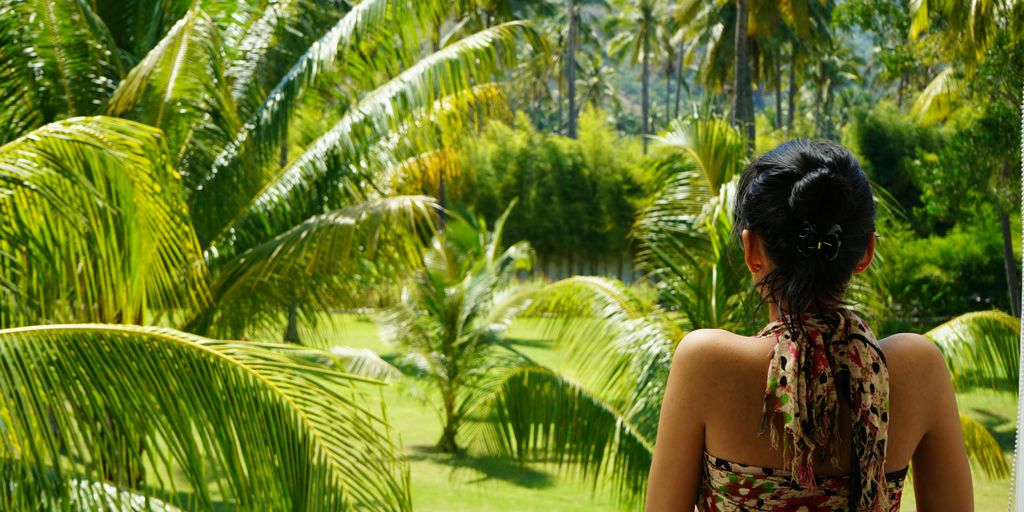 A woman looking out a window at a lush green forest